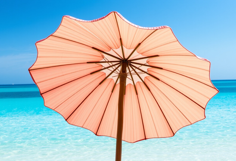Coral scallop-shell parasol by turquoise water